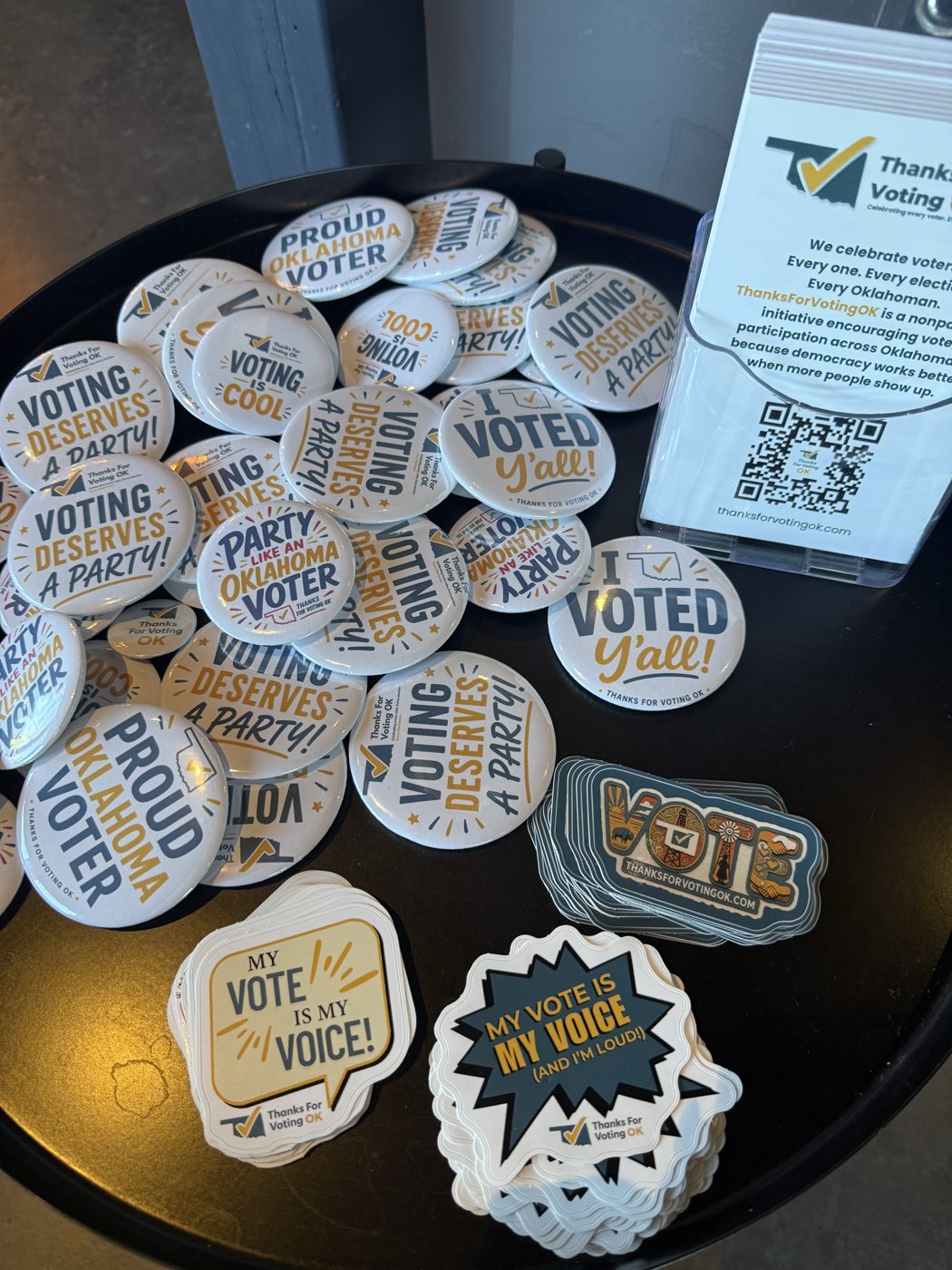 A tray of Thanks For Voting OK buttons and stickers reading Voting Deserves a Party, Proud Oklahoma Voter, and I Voted Y'all
